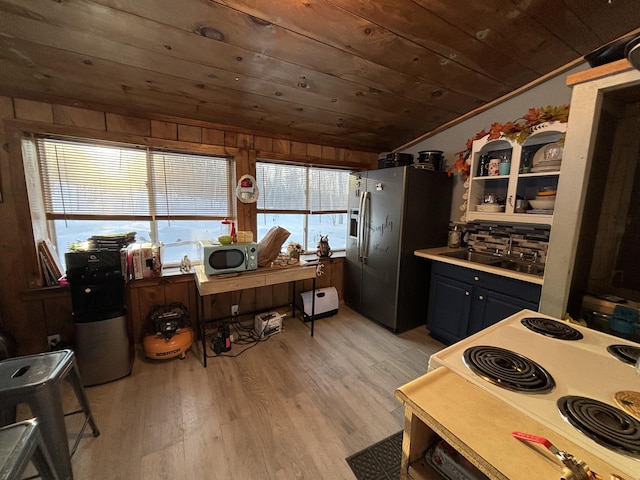 kitchen featuring light wood finished floors, wooden ceiling, appliances with stainless steel finishes, vaulted ceiling, and a sink