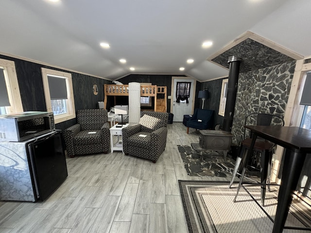 living room with a wood stove, recessed lighting, wood finished floors, and lofted ceiling