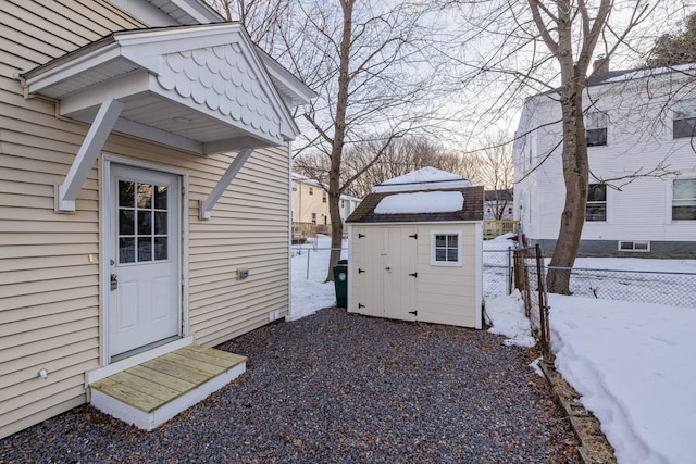 yard covered in snow featuring an outbuilding, a fenced backyard, and a shed