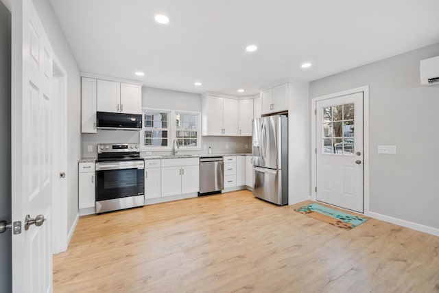 kitchen featuring light wood-style flooring, recessed lighting, stainless steel appliances, a sink, and white cabinetry