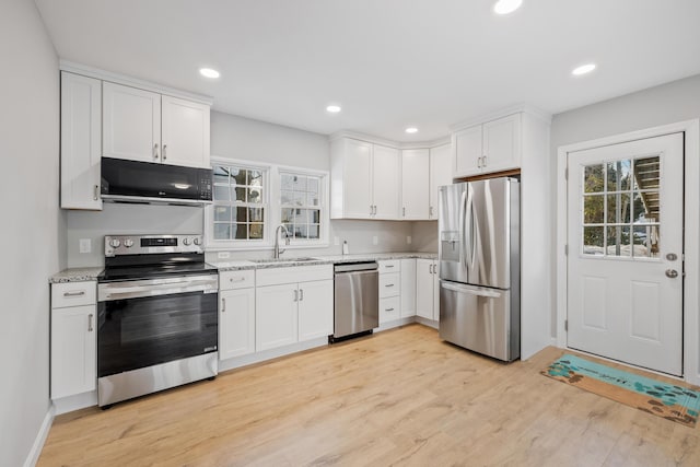 kitchen with light wood-type flooring, white cabinetry, stainless steel appliances, and a sink