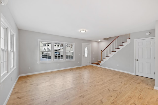 foyer featuring stairs, baseboards, and light wood-style floors