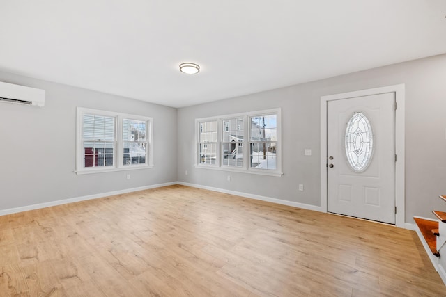 entrance foyer featuring light wood finished floors, baseboards, and an AC wall unit