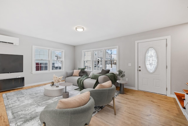 living area with an AC wall unit, light wood finished floors, a wealth of natural light, and baseboards