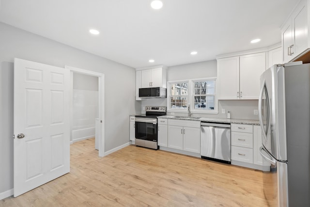 kitchen with stainless steel appliances, a sink, white cabinets, and light stone countertops