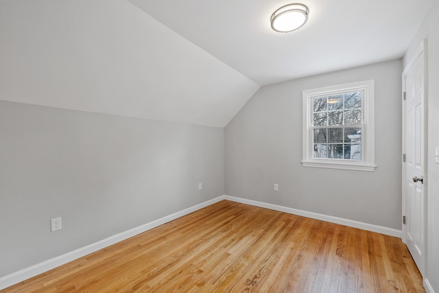 bonus room with vaulted ceiling, light wood-style flooring, and baseboards