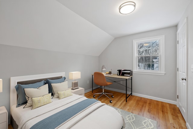 bedroom featuring lofted ceiling, baseboards, and wood finished floors