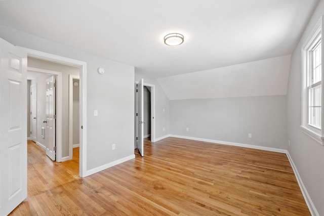 additional living space featuring light wood-type flooring, baseboards, and vaulted ceiling