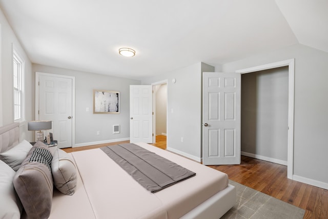 bedroom featuring vaulted ceiling, wood finished floors, visible vents, and baseboards