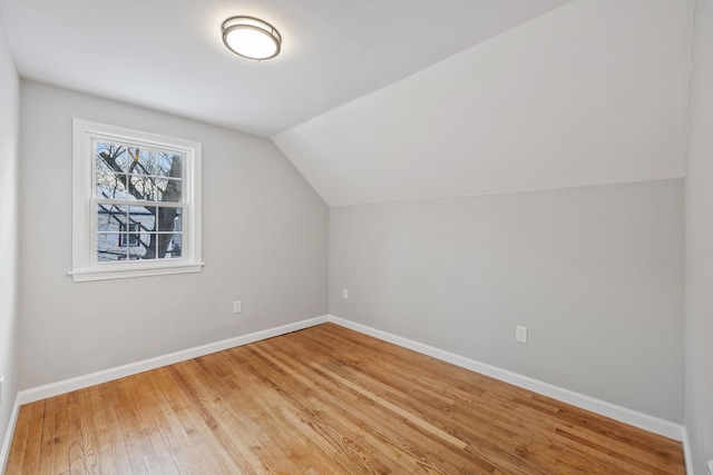 additional living space with vaulted ceiling, light wood finished floors, and baseboards