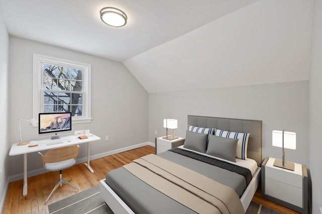 bedroom with lofted ceiling, baseboards, and wood finished floors