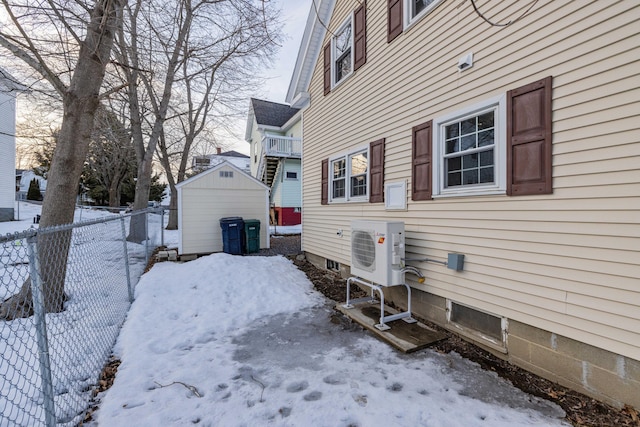 snow covered property featuring ac unit, fence, and an outbuilding