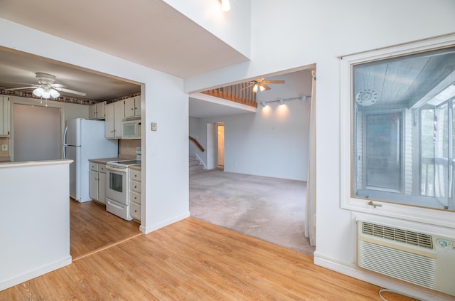 34 Parkwood Dr Unit 203, Augusta, ME 04330 - kitchen with white appliances, a ceiling fan, a wall mounted AC, light wood-type flooring, and baseboards
