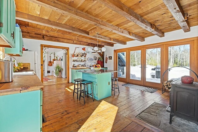 kitchen with wooden ceiling, a kitchen island, green cabinets, hardwood / wood-style floors, and a kitchen bar