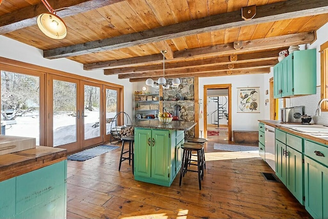 kitchen featuring tasteful backsplash, stainless steel dishwasher, green cabinets, wood ceiling, and a kitchen bar