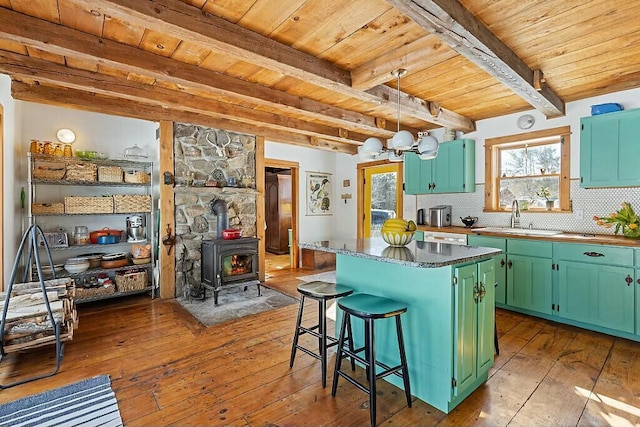 kitchen featuring wood ceiling, green cabinets, a sink, and a center island