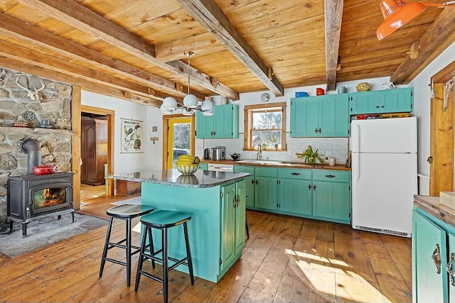 kitchen with light wood-style floors, a kitchen island, decorative backsplash, and freestanding refrigerator