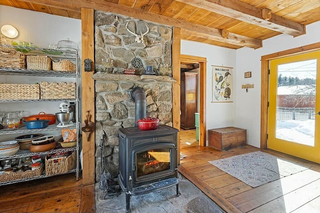 interior space with a wood stove, beamed ceiling, wood ceiling, and hardwood / wood-style flooring