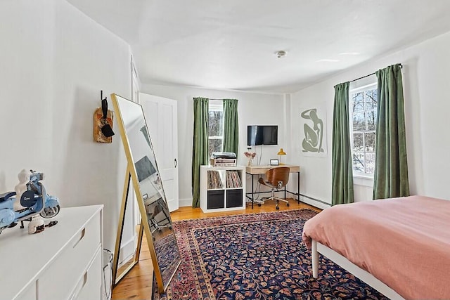 bedroom featuring light wood finished floors and baseboards