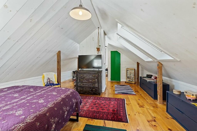 bedroom featuring lofted ceiling with skylight, wood-type flooring, and wooden walls