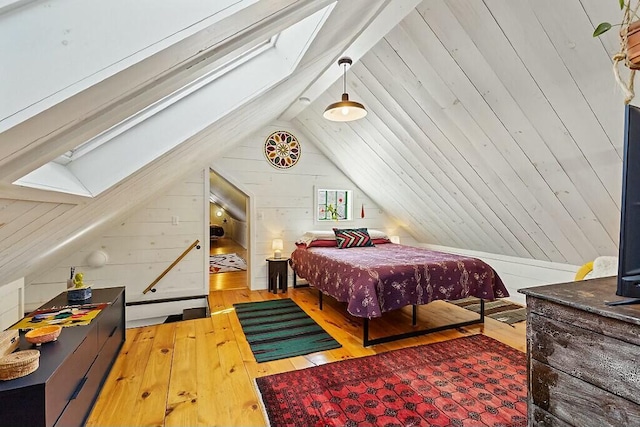 bedroom featuring vaulted ceiling with skylight, wooden walls, and hardwood / wood-style floors