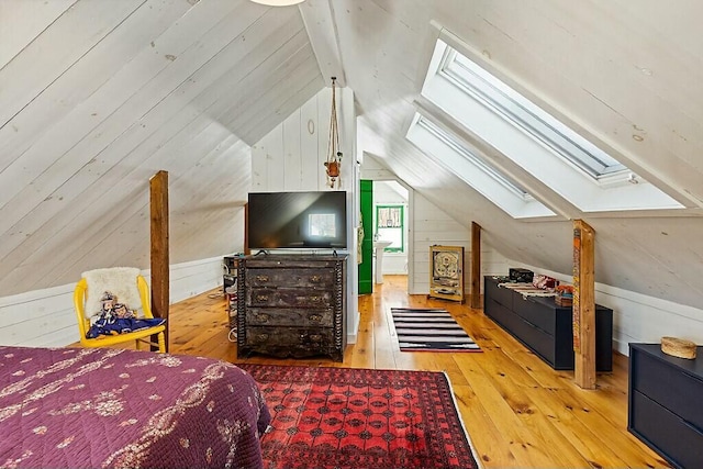 bedroom with vaulted ceiling with skylight, hardwood / wood-style floors, and wood walls