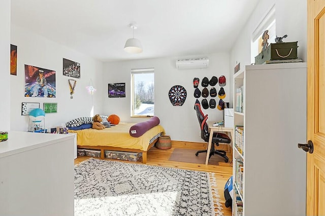 bedroom with wood finished floors and a wall mounted AC