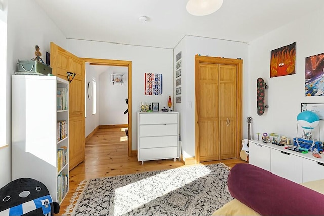 bedroom featuring light wood-style floors, baseboards, and a closet