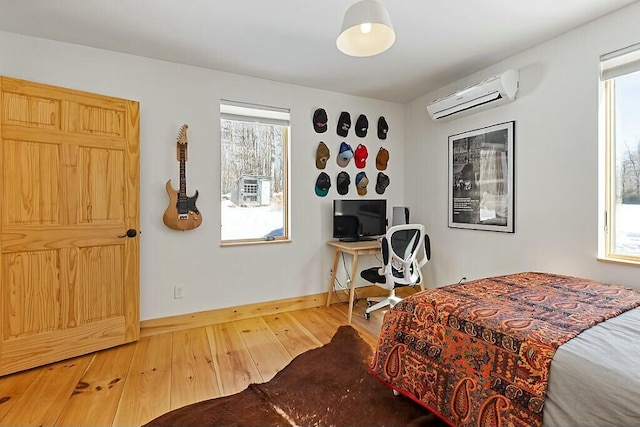 bedroom featuring an AC wall unit, hardwood / wood-style floors, and baseboards