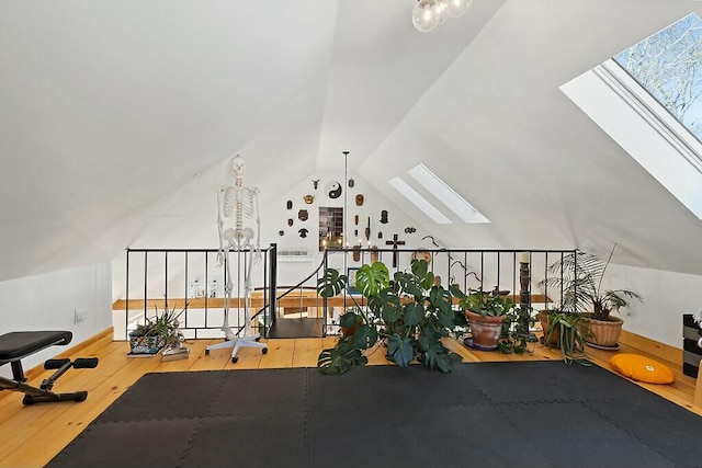 exercise room featuring vaulted ceiling with skylight and wood finished floors