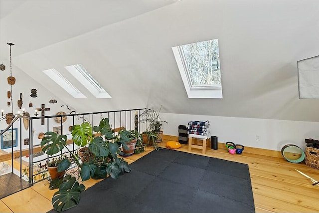 exercise area with lofted ceiling with skylight and wood finished floors