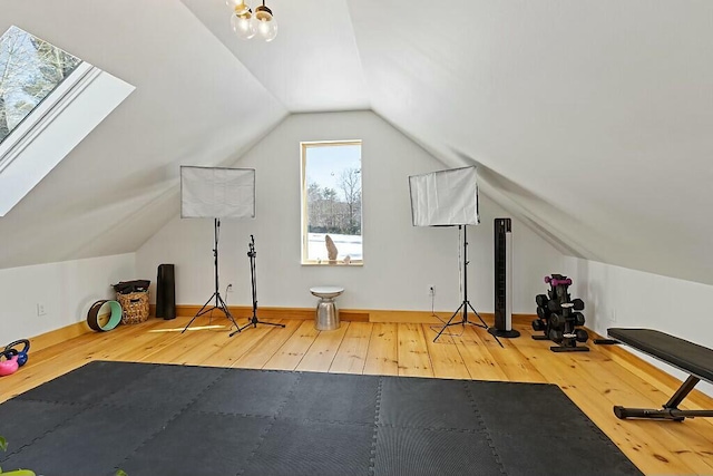 exercise area featuring vaulted ceiling with skylight and wood-type flooring