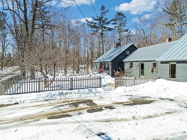 exterior space with a standing seam roof, a fenced front yard, a chimney, and metal roof