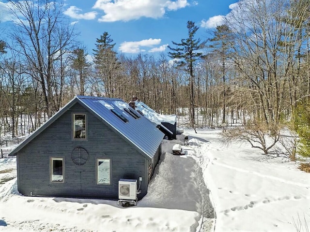 view of snow covered exterior with ac unit and metal roof