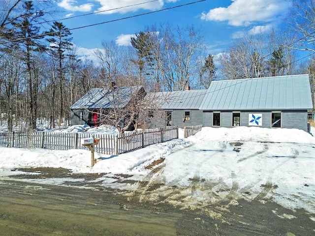 view of front facade with a fenced front yard, a standing seam roof, and metal roof