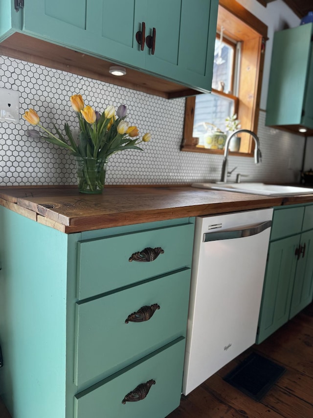 kitchen with white dishwasher, butcher block counters, a sink, tasteful backsplash, and green cabinetry