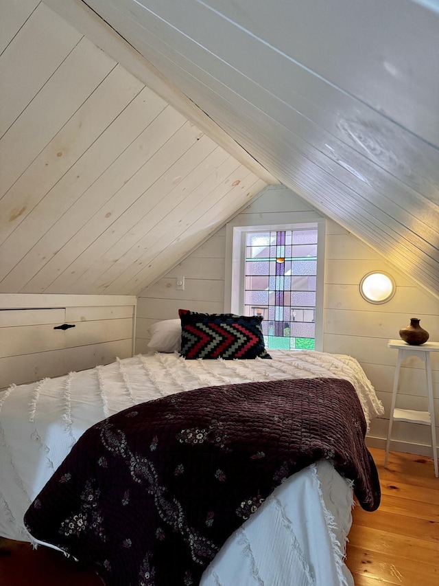 bedroom with lofted ceiling, wood walls, wooden ceiling, and wood finished floors