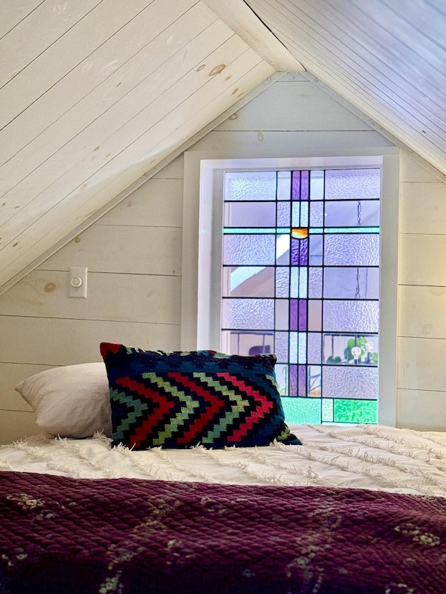 bedroom with lofted ceiling and wooden walls