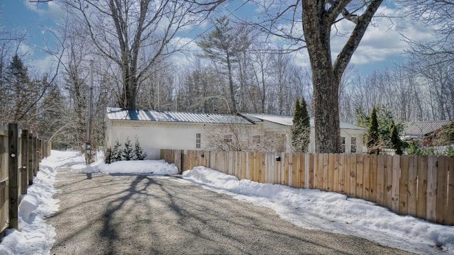 snow covered property featuring metal roof and fence private yard