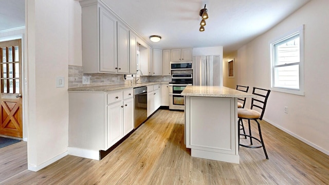 kitchen with a breakfast bar, a sink, stainless steel appliances, tasteful backsplash, and a center island