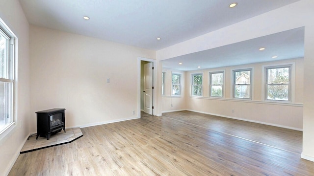 unfurnished living room with recessed lighting, a wood stove, and wood finished floors