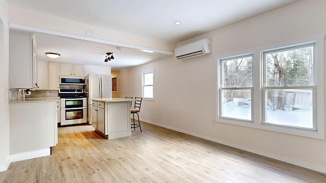 kitchen with a kitchen island, a breakfast bar, an AC wall unit, light countertops, and light wood-style floors