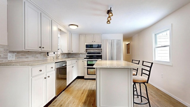 kitchen with a kitchen island, a breakfast bar area, decorative backsplash, appliances with stainless steel finishes, and a sink