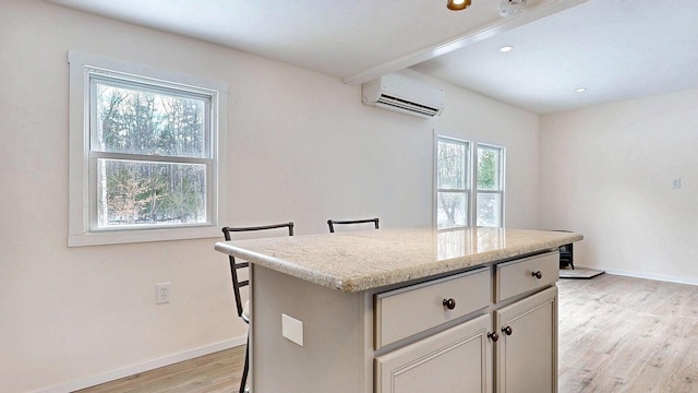 kitchen with light wood-style floors, a kitchen island, a wall mounted air conditioner, and a healthy amount of sunlight