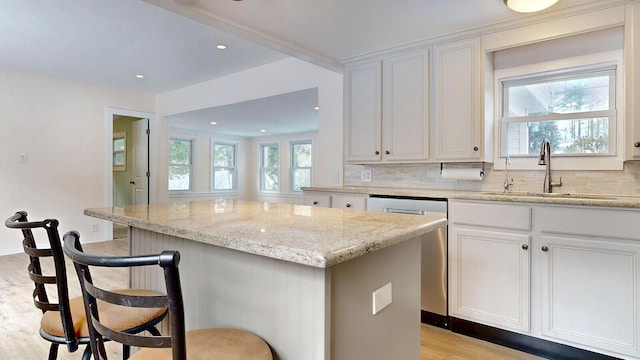 kitchen featuring decorative backsplash, a breakfast bar area, a center island, and a sink