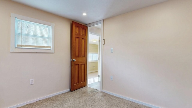 unfurnished room with baseboards and light carpet