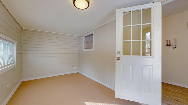 spare room featuring wooden walls, baseboards, and wood finished floors