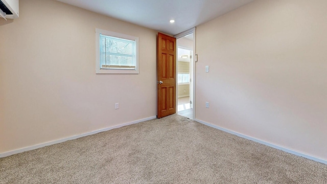 spare room with a wall mounted air conditioner, baseboards, light colored carpet, and recessed lighting