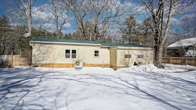 snow covered property with fence and metal roof