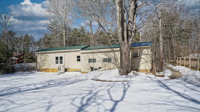 view of front of property featuring metal roof, central AC, and fence